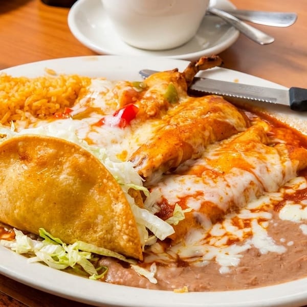 A plate of Mexican food with enchiladas, rice, refried beans, and a crispy taco.