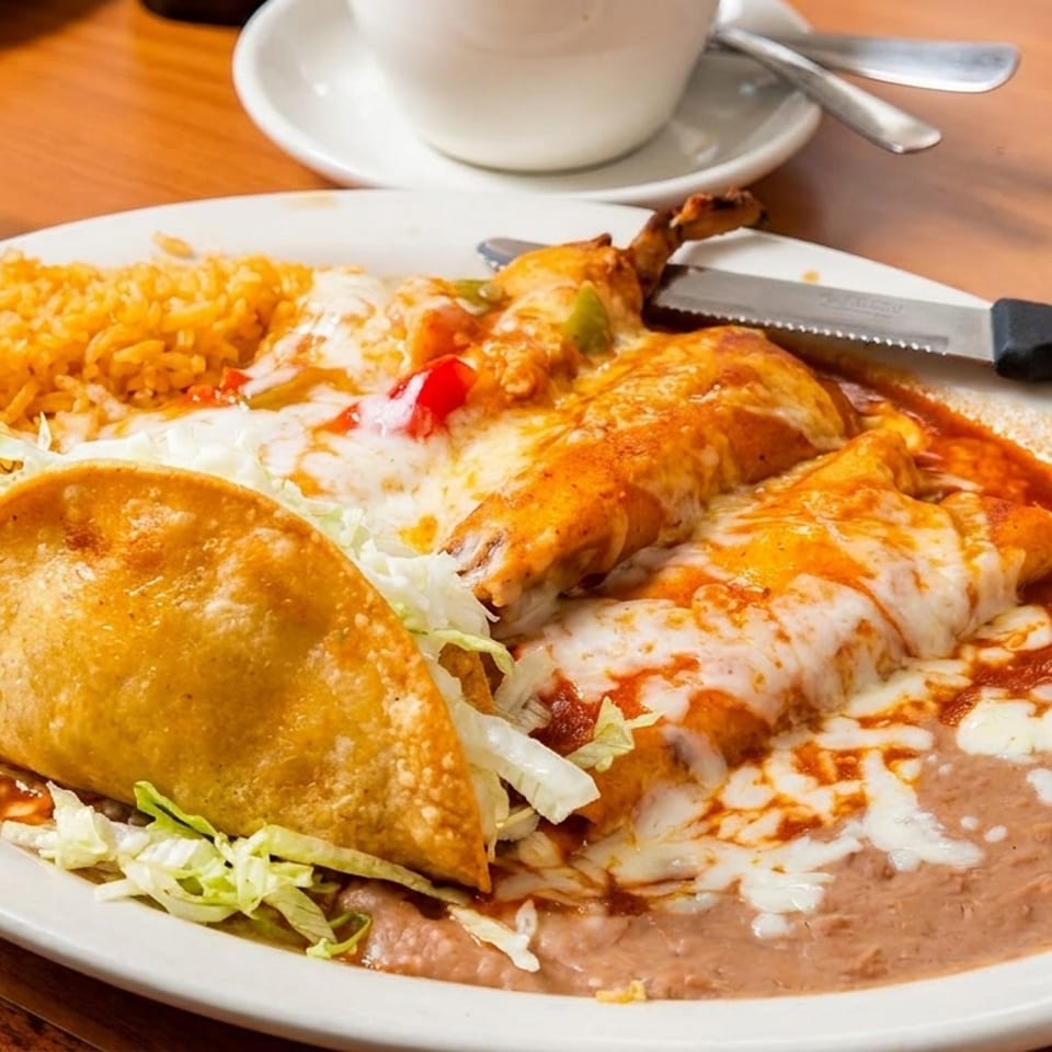 A plate of Mexican food with a crispy taco, enchiladas, rice, and refried beans.